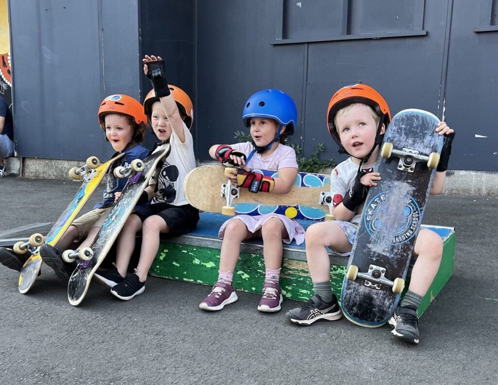 Four happy young skateboarders having a blast on a skateboard ramp during a Skate Now kids skate party