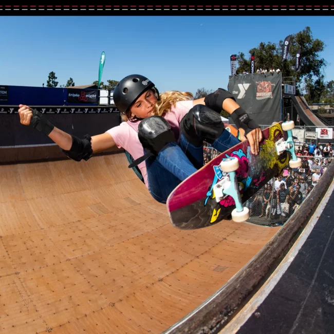 Young girl in mid-air on a vert ramp, wearing 187 Killer Pads and Helmet for protection.