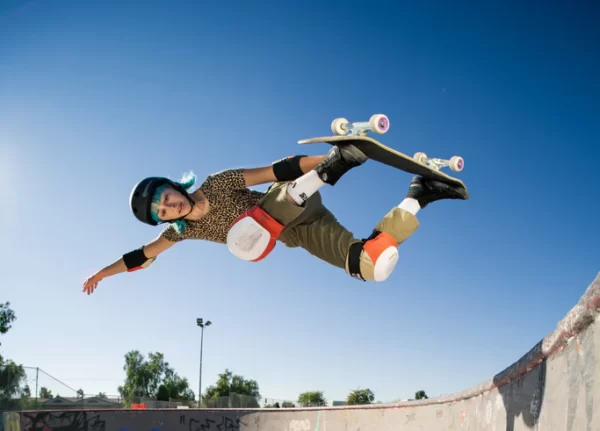 Lizzie Armanto performing a backside air in a skatepark with a blue sky in the background