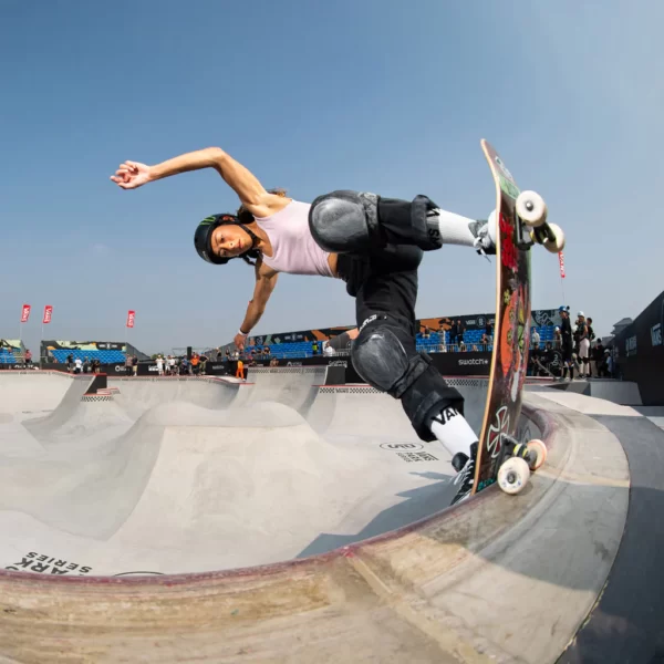 Lizzie Armanto performing a backside bluntslide in a skatepark with a blue sky in the background