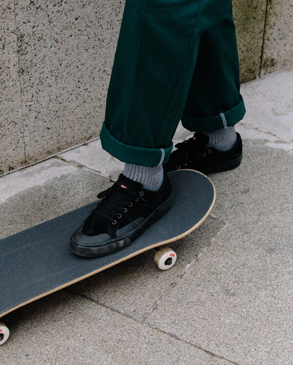 Skater stepping on Globe Goodstock complete skateboard in urban environment