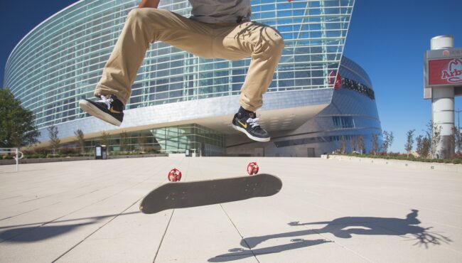 Skateboarder mid-kickflip with a board with Skater Trainers