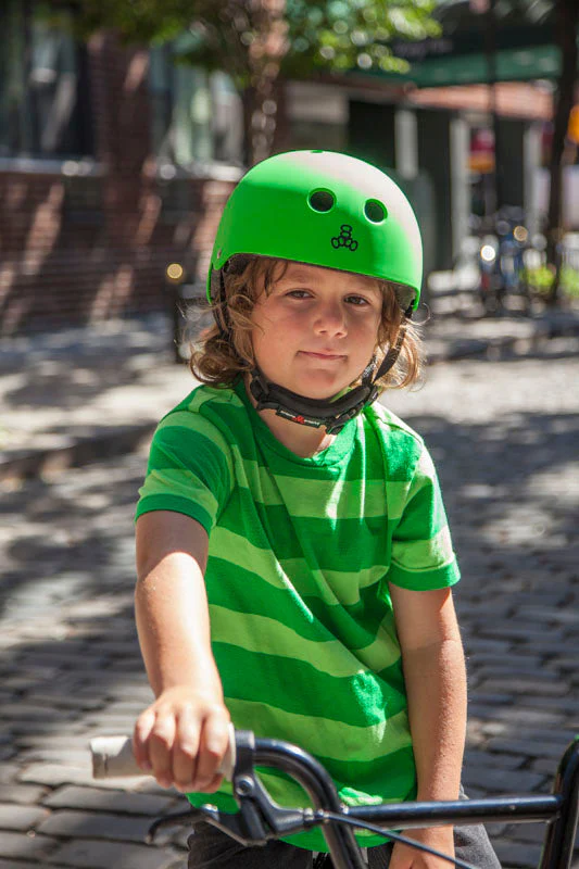 Kid on a bike wearing a neon green glossy Lil 8 helmet and stripey green shirt