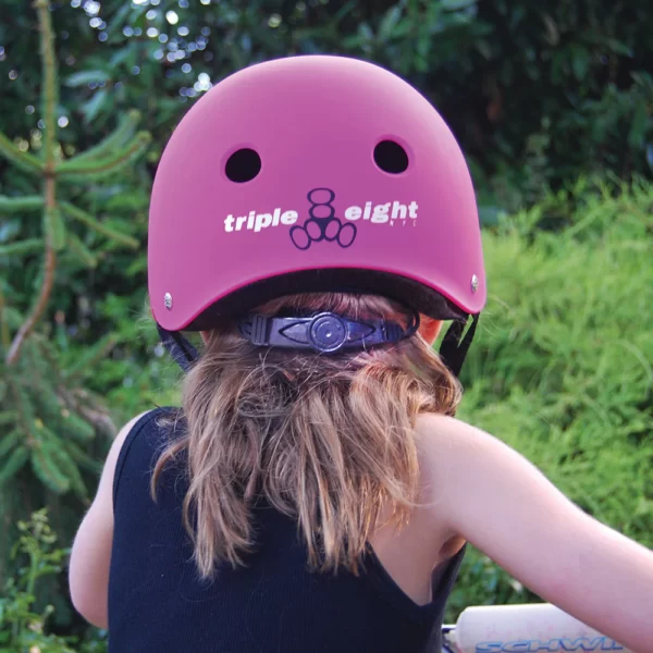 Girl on a bike wearing neon pink rubber Lil 8 helmet.