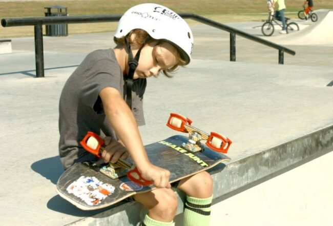 Young skater removing Skater Trainers at skatepark